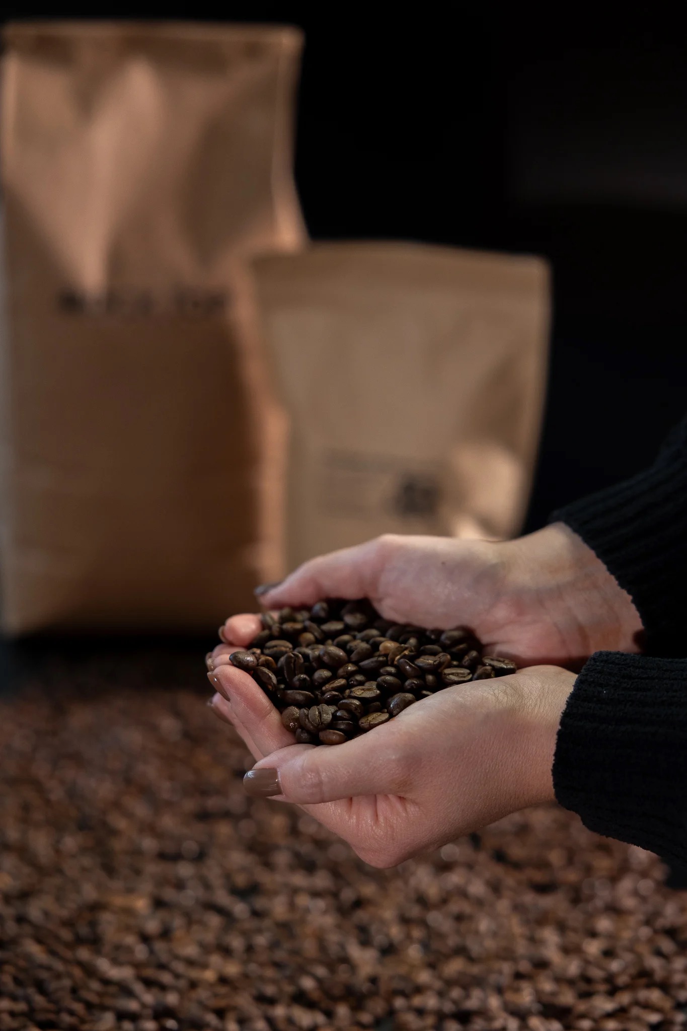 Freshly roasted beans held over kraft coffee bags ready to ship